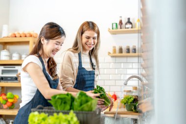 Gülümseyen kadınlar taze sağlıklı salata sebzeleri hazırlıyorlar. Güzel bir iç mutfakta kilerde duran bir kadın. Yerel ürünlerden ve malzemelerden alınan temiz diyet gıdaları taze pazardır..