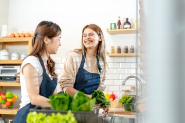Gülümseyen kadınlar taze sağlıklı salata sebzeleri hazırlıyorlar. Güzel bir iç mutfakta kilerde duran bir kadın. Yerel ürünlerden ve malzemelerden alınan temiz diyet gıdaları taze pazardır..
