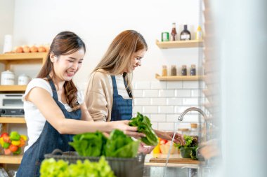 Gülümseyen kadınlar taze sağlıklı salata sebzeleri hazırlıyorlar. Güzel bir iç mutfakta kilerde duran bir kadın. Yerel ürünlerden ve malzemelerden alınan temiz diyet gıdaları taze pazardır..