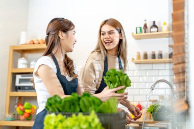 Genç kadınlar salata sebzeli sağlıklı yemek hazırlıyorlar. Bir kadın güzel bir iç mutfakta kilerde dikiliyor. Yerel ürünlerden ve malzemelerden alınan temiz diyet gıdaları taze pazardır..