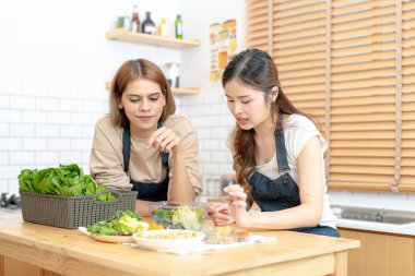 Gülümseyen kadınlar taze sağlıklı salata sebzeleri hazırlıyorlar. Güzel bir iç mutfakta kilerde oturan bir kadın. Yerel ürünlerden ve malzemelerden alınan temiz diyet gıdaları taze pazardır..