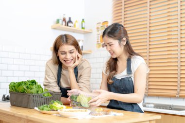 Gülümseyen kadınlar taze sağlıklı salata sebzeleri hazırlıyorlar. Güzel bir iç mutfakta kilerde oturan bir kadın. Yerel ürünlerden ve malzemelerden alınan temiz diyet gıdaları taze pazardır..