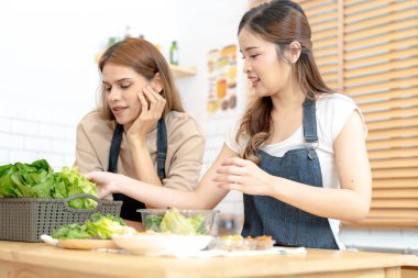 Gülümseyen kadınlar taze sağlıklı salata sebzeleri hazırlıyorlar. Güzel bir iç mutfakta kilerde oturan bir kadın. Yerel ürünlerden ve malzemelerden alınan temiz diyet gıdaları taze pazardır..