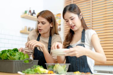 Gülümseyen kadınlar taze sağlıklı salata sebzeleri hazırlıyorlar. Güzel bir iç mutfakta kilerde oturan bir kadın. Yerel ürünlerden ve malzemelerden alınan temiz diyet gıdaları taze pazardır..