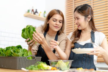 Gülümseyen kadınlar taze sağlıklı salata sebzeleri hazırlıyorlar. Güzel bir iç mutfakta kilerde oturan bir kadın. Yerel ürünlerden ve malzemelerden alınan temiz diyet gıdaları taze pazardır..
