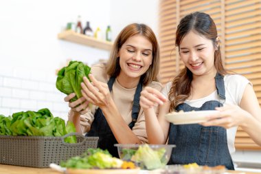 Gülümseyen kadınlar taze sağlıklı salata sebzeleri hazırlıyorlar. Güzel bir iç mutfakta kilerde oturan bir kadın. Yerel ürünlerden ve malzemelerden alınan temiz diyet gıdaları taze pazardır..