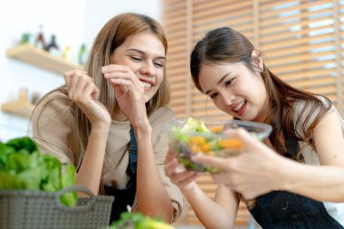 Gülümseyen kadınlar taze sağlıklı salata sebzeleri hazırlıyorlar. Güzel bir iç mutfakta kilerde oturan bir kadın. Yerel ürünlerden ve malzemelerden alınan temiz diyet gıdaları taze pazardır..