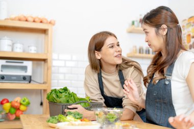 Gülümseyen kadınlar taze sağlıklı salata sebzeleri hazırlıyorlar. Güzel bir iç mutfakta kilerde oturan bir kadın. Yerel ürünlerden ve malzemelerden alınan temiz diyet gıdaları taze pazardır..