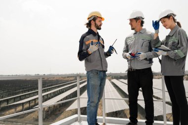 Mühendisler çatıdaki güneş panelini kontrol etmek için toplanıyor. Super Energy Corporation Specialists tarafından işletilen bir enerji depolama sistemine sahip güneş çiftliği Photovoltaic cells modülü için toplandı.