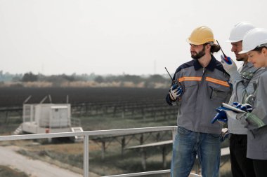 Mühendisler çatıdaki güneş panelini kontrol etmek için toplanıyor. Super Energy Corporation Specialists tarafından işletilen bir enerji depolama sistemine sahip güneş çiftliği Photovoltaic cells modülü için toplandı.