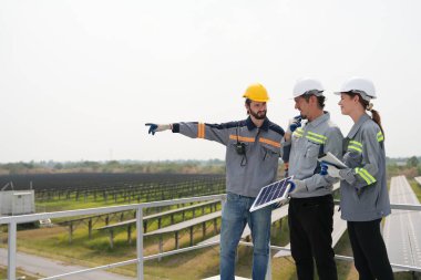 Mühendisler çatıdaki güneş panelini kontrol etmek için toplanıyor. Super Energy Corporation Specialists tarafından işletilen bir enerji depolama sistemine sahip güneş çiftliği Photovoltaic cells modülü için toplandı.