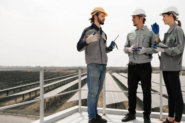 Mühendisler çatıdaki güneş panelini kontrol etmek için toplanıyor. Super Energy Corporation Specialists tarafından işletilen bir enerji depolama sistemine sahip güneş çiftliği Photovoltaic cells modülü için toplandı.