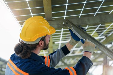 Fabrika mühendisi güneş paneli inşaatını kontrol ediyor ve onarıyor. İşçi yenilenebilir enerji için güneş enerjisi çiftliğinde çalışıyor. Sürdürülebilirlik için güneş pili endüstrisi.