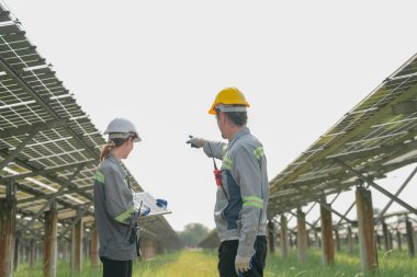 Güneş çiftliğindeki fotovoltaik hücre modülünün enerji depolama sistemi ile test edilmesi için toplanan uzmanlar.