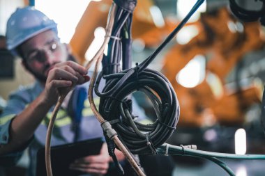 Makinedeki kablolu elektriği kontrol eden fabrika mühendisi. İşçi fabrikadaki ağır makinede çalışıyor..