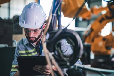 Makinedeki kablolu elektriği kontrol eden fabrika mühendisi. İşçi fabrikadaki ağır makinede çalışıyor..
