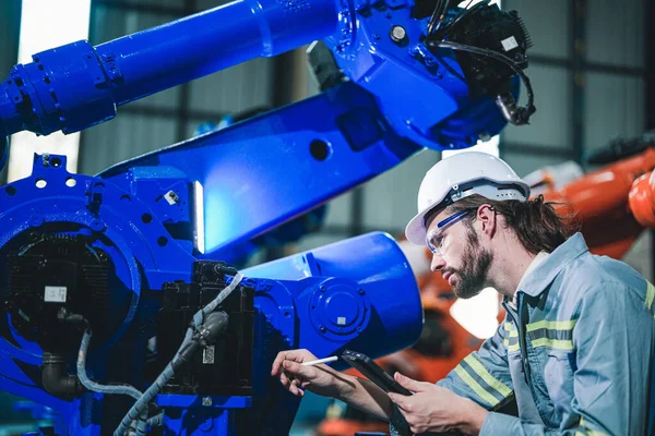 工厂工程师用智能平板机对机器进行检查 工人在重型机械机械臂上工作 在某工业工厂配备远程系统的焊机 人工智能概念 — 图库照片