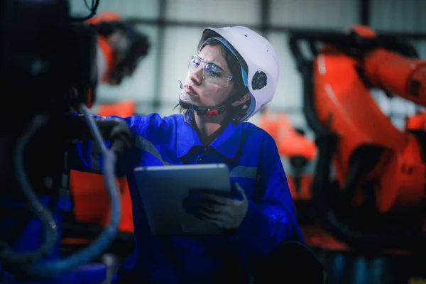 工厂女工程师用智能平板机对机器进行检查 工人们在机械机械臂上工作 在某工业工厂配备远程系统的焊机 人工智能概念 — 图库照片