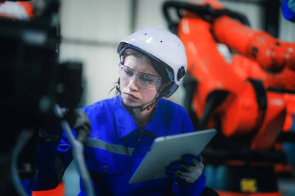 工厂女工程师用智能平板机对机器进行检查 工人们在机械机械臂上工作 在某工业工厂配备远程系统的焊机 人工智能概念 — 图库照片