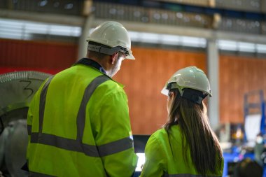 Profesyonel mühendisler depo fabrikasına girip kontrol ediyorlar. Yönetici, iç denetim için teftiş raporunu tartışıyor. Üretim için kalite güvencesi. Konsept Mühendisi.