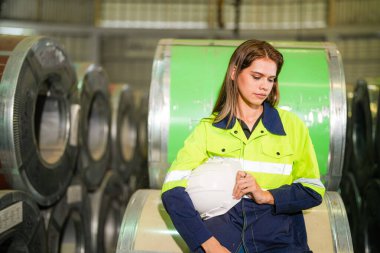Fabrika işçisi çelik rulo üzerinde oturuyor ve stres altında fabrika atölyesinde başarısız oluyor..