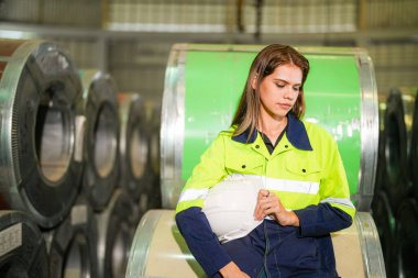 Fabrika işçisi çelik rulo üzerinde oturuyor ve stres altında fabrika atölyesinde başarısız oluyor..