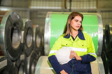 Fabrika işçisi çelik rulo üzerinde oturuyor ve stres altında fabrika atölyesinde başarısız oluyor..