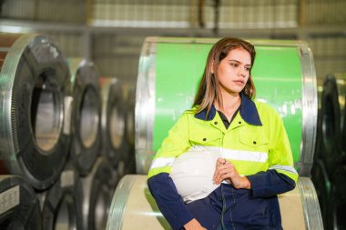 Fabrika işçisi çelik rulo üzerinde oturuyor ve stres altında fabrika atölyesinde başarısız oluyor..