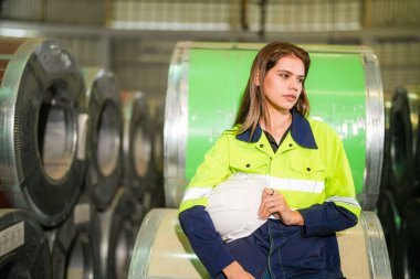 Fabrika işçisi çelik rulo üzerinde oturuyor ve stres altında fabrika atölyesinde başarısız oluyor..