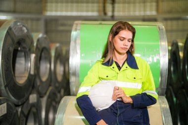 Fabrika işçisi çelik rulo üzerinde oturuyor ve stres altında fabrika atölyesinde başarısız oluyor..