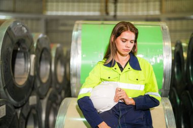 Fabrika işçisi çelik rulo üzerinde oturuyor ve stres altında fabrika atölyesinde başarısız oluyor..
