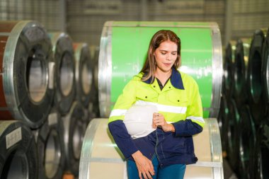 Fabrika işçisi çelik rulo üzerinde oturuyor ve stres altında fabrika atölyesinde başarısız oluyor..