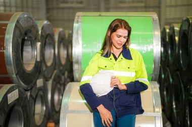 Fabrika işçisi çelik rulo üzerinde oturuyor ve stres altında fabrika atölyesinde başarısız oluyor..