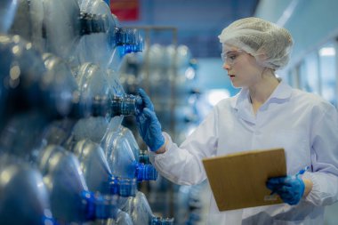 Fabrika işçisi depodaki su şişelerini kontrol ediyor.