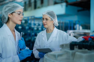 Endüstriyel fabrikadaki ters osmoz makinesinin kalitesini kontrol eden bir bilim adamı. Su deposunda veri kaydeden bir kadın işçi..