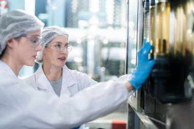 Endüstriyel fabrikadaki ters osmoz makinesinin kalitesini kontrol eden bir bilim adamı. Geri dönüşümlü taşınabilir bitki için ölçüm tüpü ile kontrol panelinde veri kaydeden kadın işçi.