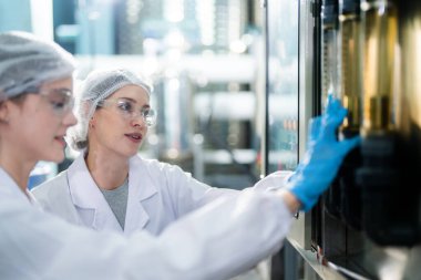 Endüstriyel fabrikadaki ters osmoz makinesinin kalitesini kontrol eden bir bilim adamı. Geri dönüşümlü taşınabilir bitki için ölçüm tüpü ile kontrol panelinde veri kaydeden kadın işçi.