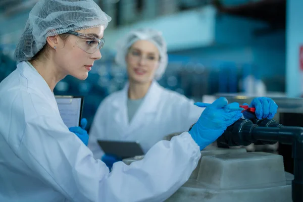 科学者の労働者は 工業工場で逆浸透機械システムの品質をチェックします 水タンクでデータを記録する女性労働者 — ストック写真