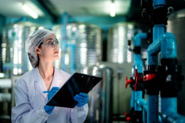 Endüstriyel fabrikadaki ters osmoz makinesinin kalitesini kontrol eden bilim adamı. Geri dönüşümlü taşınabilir fabrika için ölçü basıncıyla kontrol panelinde veri kaydeden kadın işçi.