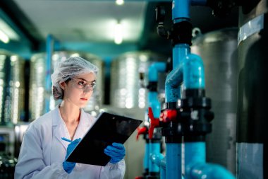 Endüstriyel fabrikadaki ters osmoz makinesinin kalitesini kontrol eden bilim adamı. Geri dönüşümlü taşınabilir fabrika için ölçü basıncıyla kontrol panelinde veri kaydeden kadın işçi.