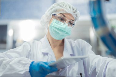 Kadın fabrika işçileri endüstriyel fabrikadaki makine sistemlerini kontrol ediyorlar. Kadınlar içecek ve gıda üretimi için temiz odalarda çalışıyorlar