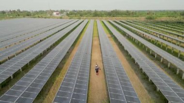 Güneş panelini kontrol etmek için güneş çiftliğinde yürüyen işçilerin en iyi görüntüsü. Mühendisler güneş pili panelinin yapımını denetliyor. İHA uçuşu güneş panelleri üzerinde uçar yenilenebilir yeşil enerji alanı üzerinde.
