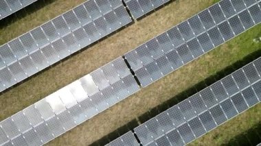 Güneş panellerini kontrol eden ve güneş çiftliğinde yürüyen mühendislerin en iyi hava görüntüsü. Mühendisler güneş pili panelinin yapımını denetliyor. İnsansız hava aracı güneş panelleri üzerinde uçuyor yenilenebilir yeşil enerji alanı üzerinde.