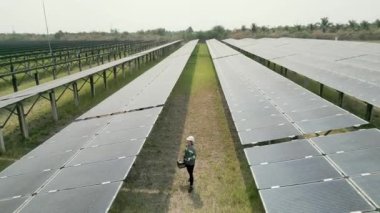 Mühendis kadın güneş pili panelinin yapımını denetliyor. Yeşil enerjinin endüstriyel yenilenebilir enerjisi. Güneş pili panelinin güneş çiftliğindeki en üst hava görüntüsü. Endüstriyel yenilenebilir enerji.