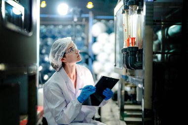 Endüstriyel fabrikadaki ters osmoz makinesinin kalitesini kontrol eden bilim adamı. Geri dönüşümlü taşınabilir fabrika için ölçü basıncıyla kontrol panelinde veri kaydeden kadın işçi.