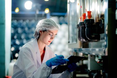 Endüstriyel fabrikadaki ters osmoz makinesinin kalitesini kontrol eden bilim adamı. Geri dönüşümlü taşınabilir fabrika için ölçü basıncıyla kontrol panelinde veri kaydeden kadın işçi.