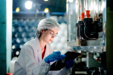 Endüstriyel fabrikadaki ters osmoz makinesinin kalitesini kontrol eden bilim adamı. Geri dönüşümlü taşınabilir fabrika için ölçü basıncıyla kontrol panelinde veri kaydeden kadın işçi.