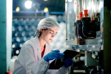 Endüstriyel fabrikadaki ters osmoz makinesinin kalitesini kontrol eden bilim adamı. Geri dönüşümlü taşınabilir fabrika için ölçü basıncıyla kontrol panelinde veri kaydeden kadın işçi.