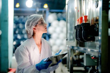 Endüstriyel fabrikadaki ters osmoz makinesinin kalitesini kontrol eden bilim adamı. Geri dönüşümlü taşınabilir fabrika için ölçü basıncıyla kontrol panelinde veri kaydeden kadın işçi.