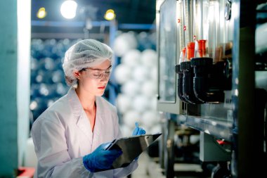 Endüstriyel fabrikadaki ters osmoz makinesinin kalitesini kontrol eden bilim adamı. Geri dönüşümlü taşınabilir fabrika için ölçü basıncıyla kontrol panelinde veri kaydeden kadın işçi.